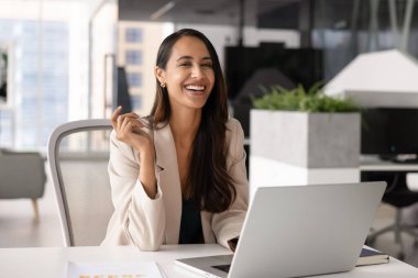 Mutlu Yeni Zelandalı iş kadını iş yerinden kameraya bakıyor, gülümsüyor, gülüyor, dizüstü bilgisayarda çalışıyor. Kendine güvenen iş kadını profesyonel portresi