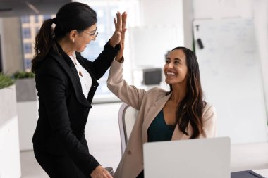 Üst düzey patron kadın, genç bayan profesyoneli iyi işi, kariyer başarısı, başarılı proje açılışı, beşlik çakma, işyerinde mutlu işçilerle el çırpma,