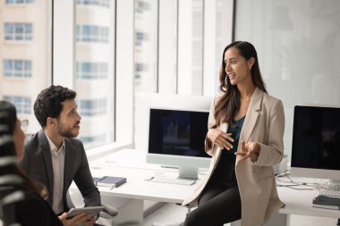 Olumlu genç proje yöneticisi kadın iş arkadaşlarıyla toplantıda konuşuyor, etkili proje yönetimi, takım çalışması, iş planı hakkında fikirler sunuyor. Takım işyerlerinde daireler çiziyor