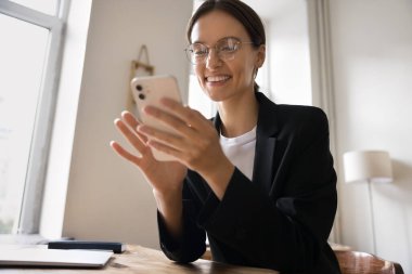 Dijital iletişimin tadını çıkar. Portre güzel başarılı milenyum iş kadını ofis masasında oturuyor gülümseyen cep telefonu aygıtı kullanıyor e-posta ödemesini bankacılık uygulamasında yazıyor ve internetten mesaj gönderiyor.