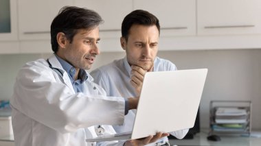 Modern teknolojiyle sağlık bilgileri veriyor. Kendine güvenen erkek doktor klinikteki hastaya danışmanlık yapıyor. Ekranda ultrason verileri gösteriyor. Teşhisi açıkla.