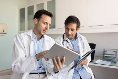 Tıbbi bakımda modern teknolojik yenilikler. Üniformalı iki doktor dijital tablet ekranına bakıp sanal 3D radyografik tarama yorumlama testi sonuçlarını tartışacaklar.