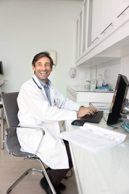 Sağlık hizmetleri evraklarında samimi kahkahalar. Neşeli dürüst erkek doktor GP hemşiresi klinikteki masabaşı işinden uzaklaşıyor. Yoğun gündüz gülüşünden kurtulmak için kısa bir ara veriyor. Profesyonel sohbetteki komik bir mesaja gülümsüyor.