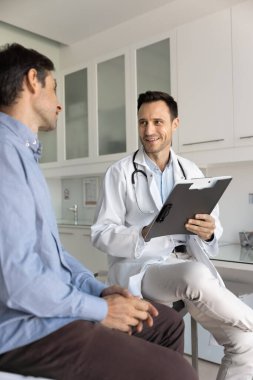 Doktorla diyalog. Dost canlısı gülümseyen, profesyonel tıp doktoru muayene odasında hasta ile randevusu var. Semptomlar hakkındaki şikayetleri dinle. Kağıt üzerinde notlar al.