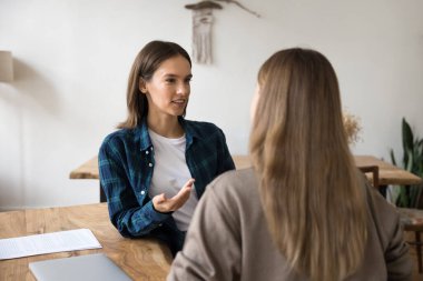 Günlük iş yerinde müşteri danışmanlığı. Kendine güvenen genç satıcı emlakçı. Konforlu ajans ofisindeki kadın müşteriye danış. Anlaşma detaylarını açıkla.