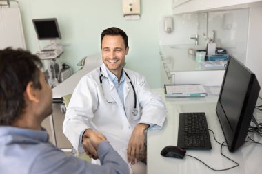 Tıp alanında güven ve işbirliği. Gülümseyen erkek terapist klinikte hasta üstüne hasta tokalaşması. Doktor ilaç temsilcisiyle anlaşma yaptı. Yeni ilaç cihazı tedavisini kabul etti.