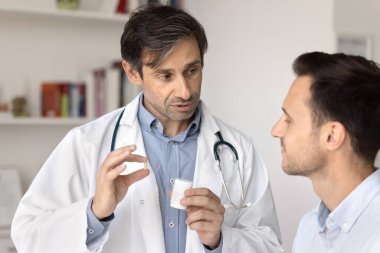 Uyuşturucu tavsiyesi ve farmakolojik danışmanlık. Profesyonel erkek doktor eczacı hastaya etkili hastalık tedavisi için yeni ilaçlar verdi.