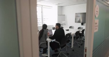 İki iş adamı dizüstü bilgisayardaki ürün pazarlama verilerini analiz ediyorlar, toplantı odasında bilgisayar başında birlikte çalışıyorlar, takım çalışması sonuçlarını tartışıyorlar, büyüme stratejisini tartışıyorlar. Gizli kamera görüntüsü.