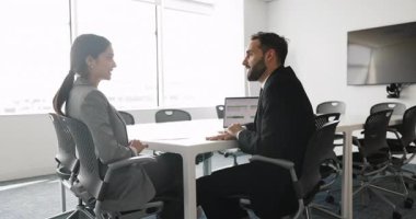 Bir çift pozitif genç iş ortağı ofis yönetim kurulunda büyük bir toplantı masasında konuşuyor, ortaklık, işbirliği, tokalaşma, gülümseme gibi konularda görüşmeler yapıyorlar.