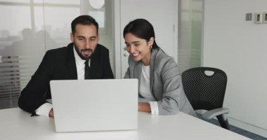 Geniş ofis masasında dizüstü bilgisayardan içeriği izleyen, video, internet ürünü, uygulama, web servisi, gülümseme tartışan iki mutlu iş arkadaşı.