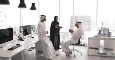 Üç kişilik Arap iş ekibi açık ofis alanında daireler çiziyor, birlikte çalışma merkezinde konuşuyor, takım çalışması, yatırım, planlama görevlerini tartışıyor, ürün geliştirme stratejisi üzerine beyin fırtınası yapıyor.