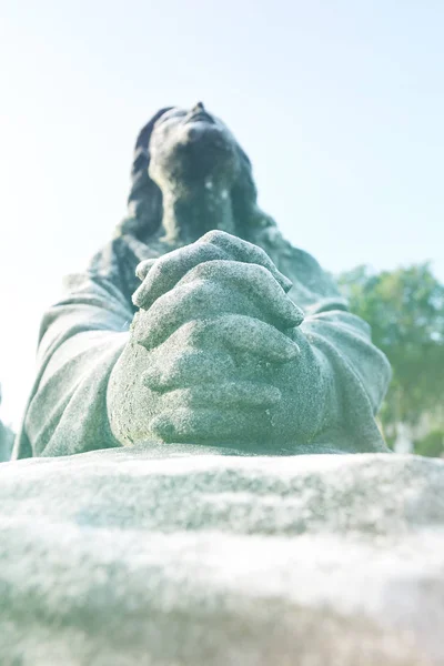 Scene of Jesus Christ praying to God, his Father. Statue or sculpture of Jesus looking up to the blue sky. Focus on the praying hands.