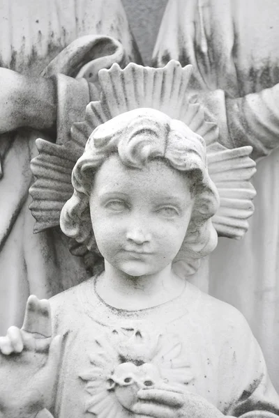 Detail of young Jesus and sacred heart with mother Mary and father Joseph behind. Statue depicting Holy Family of Jesus.