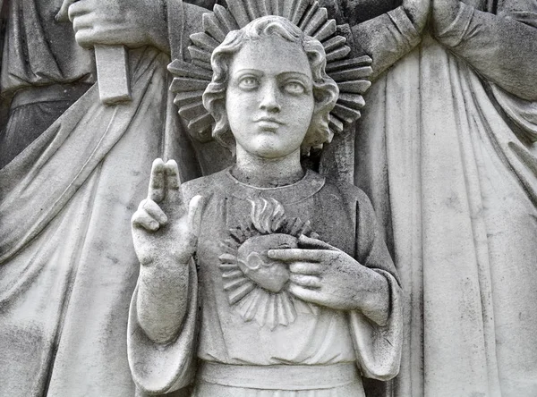 Detail of young Jesus and sacred heart with mother Mary and father Joseph behind. Statue depicting Holy Family of Jesus.