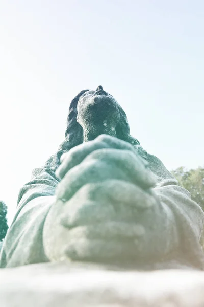 Scene of Jesus Christ praying to God, his Father. Statue or sculpture of Jesus looking up to the blue sky. Focus on the face.