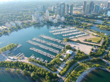 Aerial bird eye shot over Humber Bay Shores Park, Toronto, Canada with coastal condo homes, blue skies, beaches and harbour entrance in view with glass condominiums. Perfect summer day sunset. clipart