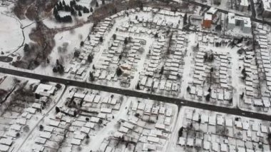 Yolların ve evlerin hava aracı görüntüsü kış manzarası. Kış kenti sokakları kuş bakışı. Karla kaplı binaların en üst perspektifi. Yollar, çimenler, arabalar ve ağaçlar karla kaplı yukarıdan.