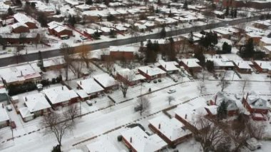 Yolların ve evlerin hava aracı görüntüsü kış manzarası. Kış kenti sokakları kuş bakışı. Karla kaplı binaların en üst perspektifi. Yollar, çimenler, arabalar ve ağaçlar karla kaplı yukarıdan.