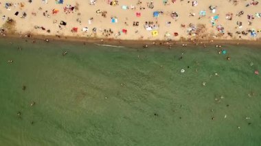 Yukarıdan görünüm, plaj şemsiyeleri ve insanlar, çocuklar ve rahatla ve yüzmek turist ile kumlu bir plaj ile yeşil su havadan görünümü.