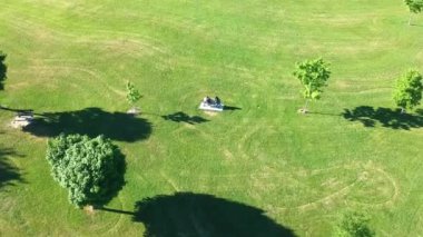 İki genç insan güneşli yaz yeşil çim spacey alanında bankta oturma yukarıda hava uçuş. Çift.