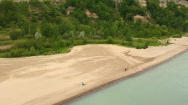 Hava deniz kıyısında kumlu plaj bazı insanlar ile desteklemek ve su yakınında sakin günler su üstünde uçan. Drone kayma üzerinde.