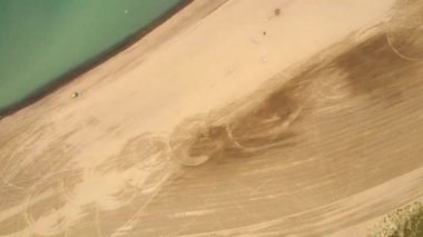 Hava deniz kıyısında kumlu plaj bazı insanlar ile desteklemek ve su yakınında sakin günler su üstünde uçan. Drone kayma üzerinde.