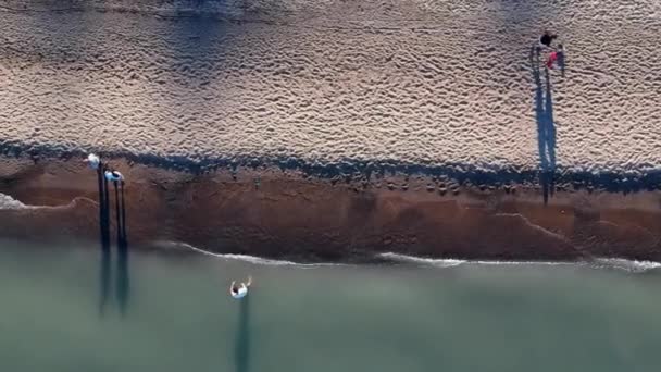 空中飞行在水面上的沙滩海岸上 在海边 有的人散步 享受水附近的平静一天 无人机滑翔过来 — 图库视频影像