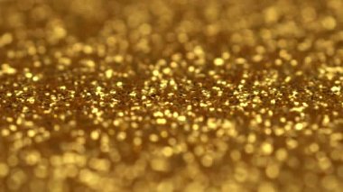 Altın parıldayan soyut sorunsuz dönen döngü hareket arka plan. Glitter parıltılar gerçek malzeme iplikten yapılmış. Yanlarda bokeh ile orta odaklanın. Uhd 4k video.