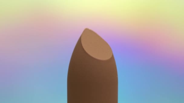 Makró lő világos bézs bőrtónusú rúzs mozgó bekapcsolja irizáló fényes háttér. Szakmai közelről smink és szépség, nyitó forgatás. Uhd 4k videó.