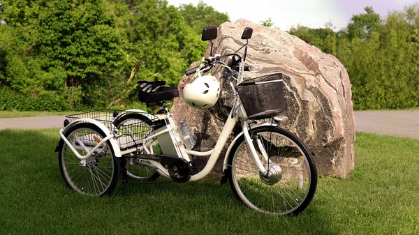 Bicicleta eléctrica en la hierba verde con fondo de piedra en el sol — Foto de Stock