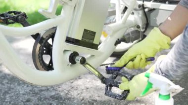 Sarı eldiven bisikletçi yaz günü dışında elektrikli bisiklet su spreyi temizleme pedalı olduğunu. Çerçevedeki güç pilinin bir parçası. Binici spor e bisiklet dikkat çekmek. 4k