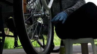 Mavi lastik eldivenli bisikletçi yaz günü dışarıda elektrikli bisiklet arka tekerleği temizliyor. Yavaş motorlu dolly çekim hareketi, Aşağıdan kaydırıcı kamyon yan hareketi kapatın. 4k