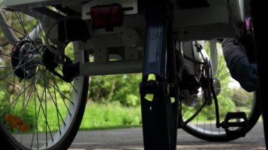 Mavi lastik eldivenli bisikletçi yaz günü dışarıda elektrikli bisiklet arka tekerleği temizliyor. Yavaş motorlu dolly çekim hareketi, Aşağıdan kaydırıcı kamyon yan hareketi kapatın. 4k