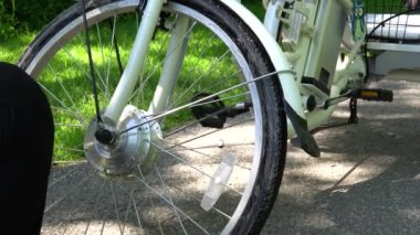 Sarı eldivenli bisikletçi yaz günü dışarıda elektrikli bisiklet motor tekerleği temizliyor. Binici motor ile spor e bisiklet tekerleği dikkat çekmek. 4k