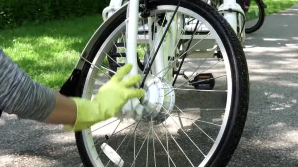 El ciclista con guantes amarillos es una toalla seca que limpia la rueda del motor de la bicicleta eléctrica en el día de verano. Jinete cuidar del deporte e rueda de bicicleta con motor. 4k — Vídeos de Stock