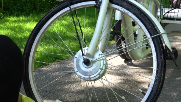 Ποδηλάτης σε κίτρινα γάντια είναι σπρέι καθαρισμό του ηλεκτρικού τροχού κινητήρα ποδηλάτων έξω κατά τη θερινή ημέρα. Ο αναβάτης φροντίζει τον τροχό του αθλητικού ποδηλάτου με κινητήρα. 4K — Αρχείο Βίντεο