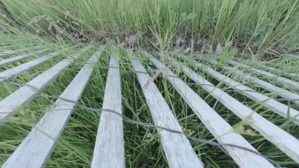 Eski çit, ahşap ve tel, yeşil çim ve yeşillik ile eski kurulları yapılmış. Köyden rustik çiftlik ten kamera görünümü. Güneşli bir yaz günü. Yavaş motorlu dolly atış hareketi, 4k. — Stok video
