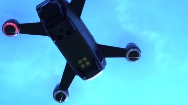 Güneşli sabahmavi gökyüzünde uçan drone aşırı yakın. Aşağıdan uçağın görüntüleri, alışılmadık bir görünüm. Yukarıda uçan quadcopter. 4k.