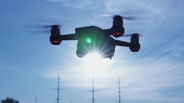 Silueta de dron girando y girando estacionario en el aire cerca de vídeo. Quadrocopter r volando sobre el sol en el soleado día de la mañana de verano. 4k . — Vídeo de stock