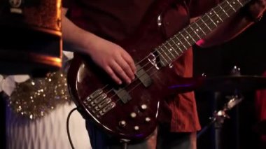 Bir konserde elektro bas gitar çalan erkek gitarist. Müzik aletinin yakın çekim. Gitarist rock festivalinde gitar dizeleri vurur.
