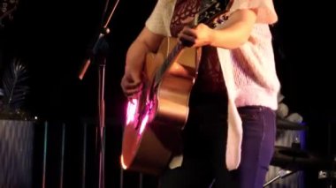 Davulcu rock konserinde davul çalar. Erkek davulcu elleri davul ile yakın müzik ritminde. Sahnede davul tabağı. Rock grubu performans sergiliyor.