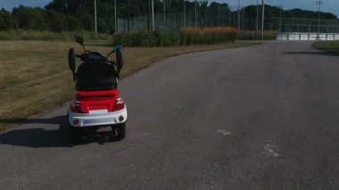 Yolda elektrikli scooter Sinematik daire dönüş görünümü. Kırmızı şık e araç. Çevreye duyarlı ulaşım yeşil şehir parkı park. Kamera kaydırma.