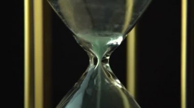 Dönen kum saati saat saati kavramı. Video açma kum saati sonunda sona eriyor. Eski vintage altın metalçerçeve yeşil kum saat yavaş yavaş koyu arka plan üzerinde dönen. Yakın çekim.