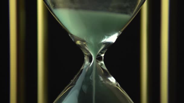 砂時計の砂のガラス粒 まだ時間のガラスは 黒い背景の上にクローズアップ 時間の概念の一過性 すべての生き生きとしているもののアイデアの時間 — ストック動画