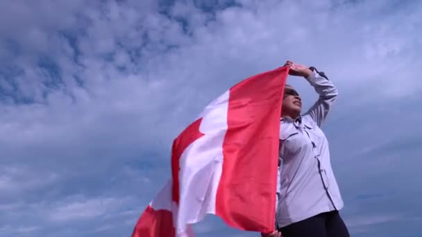 Portret van de kant van Afro-Amerikaanse vrouw met Canadese vlag tegen de wind en kijkend naar zon en blauwe bewolkte lucht. Gelukkige Canadese burger. Patriot-concept. — Stockvideo