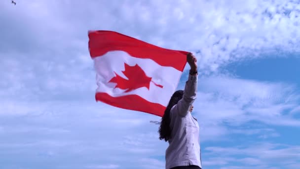 Femme adulte debout avec fierté et drapeau canadien agitant. Symbole Canada. Femme noire fière et tenant le drapeau national avec la feuille d'érable rouge debout seule sur fond bleu ciel. Concept de patriotisme ., — Video