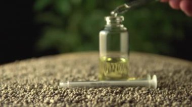 Pipette damlaları cbd yağı içerken kayıyor ve odaklanıyor. Kenevir tohumlarının üzerinde cam kavanoz. Yeni nesil sağlık eczanesi tıbbi konsepti. Acı tedavisinde devrim ve iyileşme endişesi.
