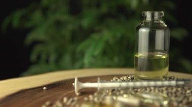 Kaygı ve stres için kullanılan Cbd yağı ve ağız şırıngası çok yakından görülüyor. Ağaç halkası masasındaki cam kavanozun yanında. Dalgalanma çizgisi desenli. Acı tedavisinde ve iyileşmede devrim.