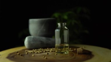 Makro yakın çekim ve küçük kavanozdaki bitkisel cbd yağın döndürülmesi ahşap halka masasında havan, tokmak ve kenevir tohumlarıyla birlikte. Tıbbi marihuana kavramının yasallaştırılması.
