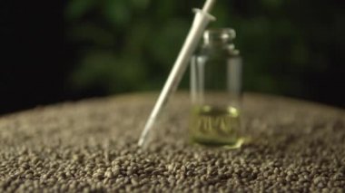 Kenevir tohumu ve yeşil marihuana bitkisi arka planında tıbbi marihuana CBD yağı ve ağız şırıngası var. Odaklan ya da yana kay. Acı tedavisinde ve iyileşmede devrim.
